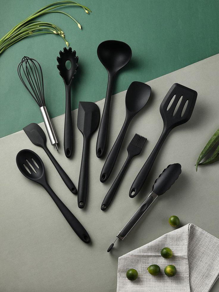 black silicone kitchen utensil set with light and dark green background, a napkin with with five small green lemons over it, and leaves on the side of the picture
