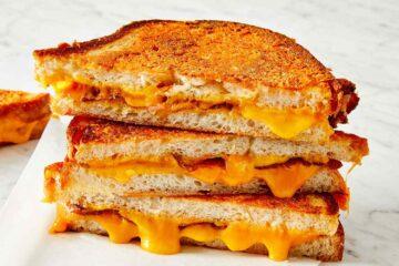 Delicious looking slices of toastie with melted cheese piled on a plate