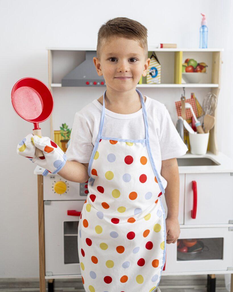 boy playing with wooden toy kitchen accessories indoors