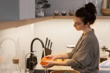 Woman wetting a kitchen sponge to wash the dishes