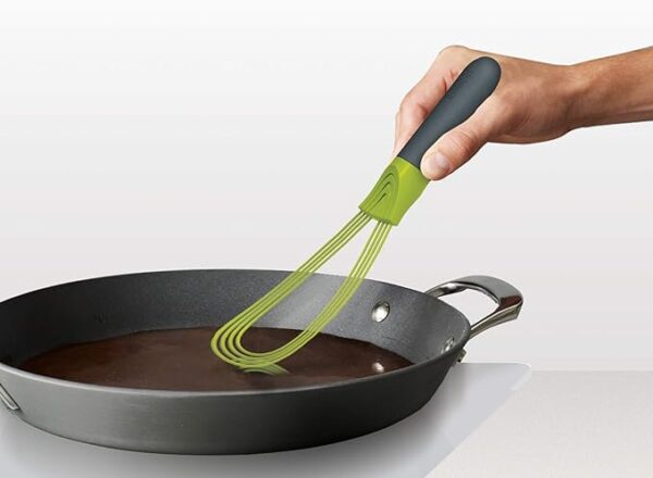 A silicon whisk with a black non stick pan