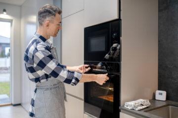 Profile of man touching toggle switch and opening oven door