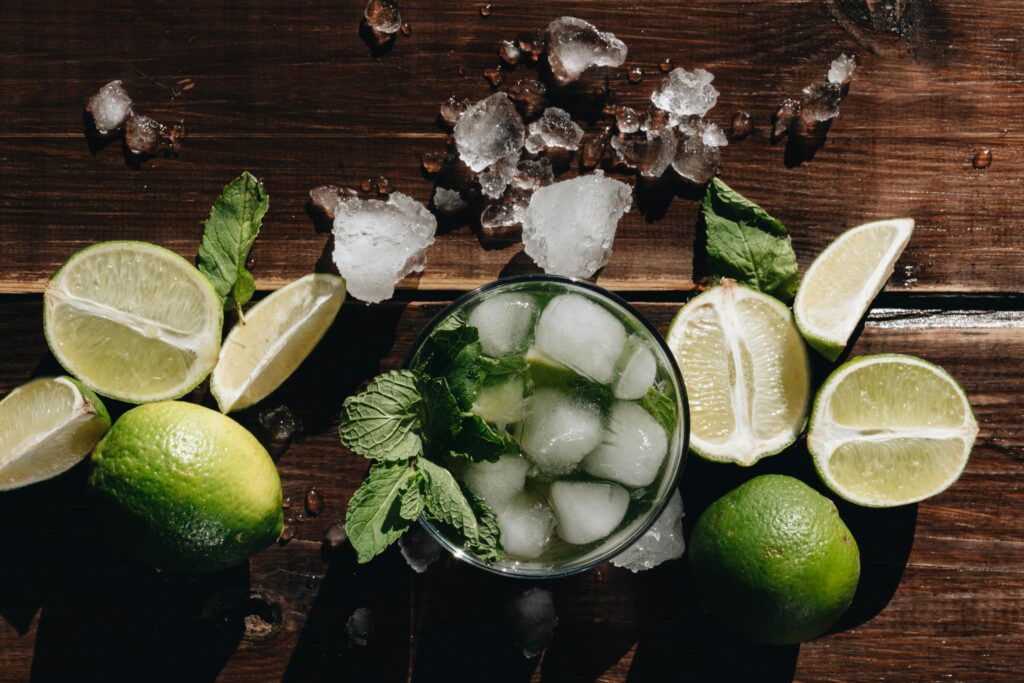 Chilled mojito cocktail with lime, mint, and ice on a rustic wooden table, perfect for summer refreshment.
