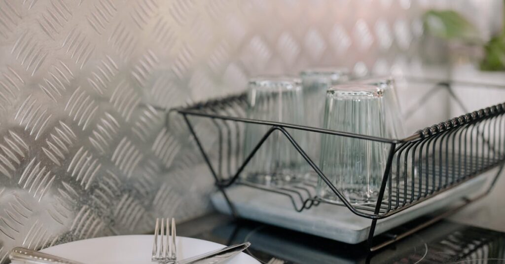 Close-up of a kitchen dish rack with glassware and utensils on a clean countertop.