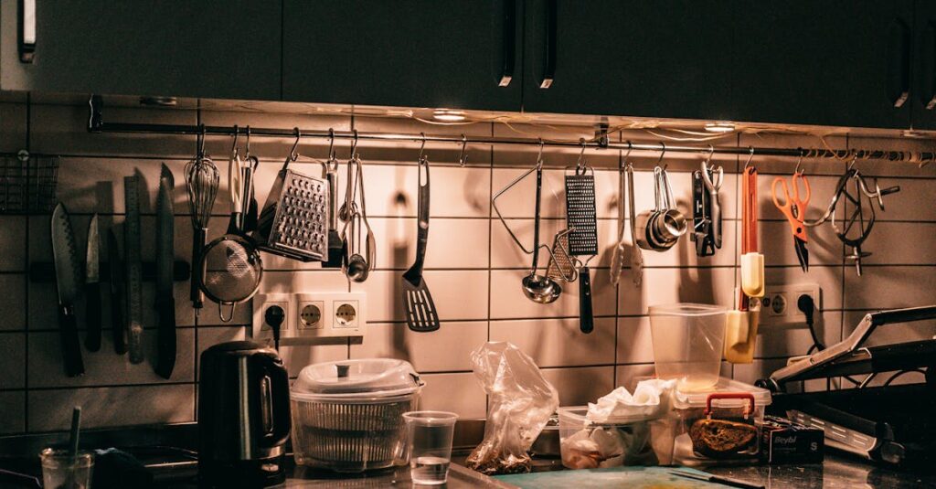 Kitchen counter with cupboards and assorted utensils hanging above table top with dishware teapot and cutting board in dark kitchen