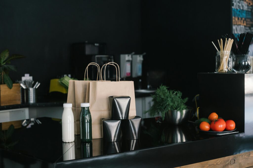 Eco-friendly takeaway packaging in a modern kitchen setting with fresh ingredients and cutlery.