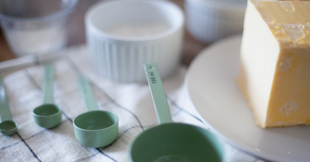 Measuring cups and butter arranged on a kitchen counter for baking preparation.